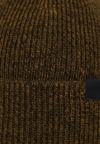 Cappello a maglia a coste marrone scuro con striature più chiare. Presenta un tessuto strutturato e un piccolo patch in pelle nera come dettaglio.