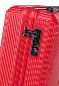 Valise rouge avec une texture striée, deux fermetures éclair noires et un verrou à combinaison. Affiche le nom de la marque "WITTCHEN" de manière proéminente.