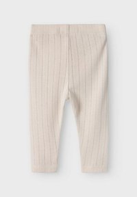 Leggings côtelés beige clair avec une texture douce, dotés d'une taille extensible et de poignets ajustés aux chevilles. Des rayures verticales discrètes améliorent le design.