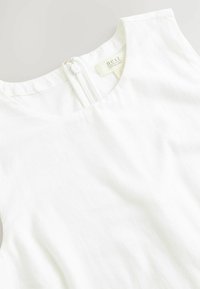Biały lniany top z okrągłym dekoltem i zamkiem błyskawicznym z tyłu. Lekko teksturowana powierzchnia o minimalistycznym designie.