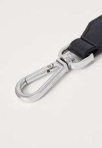 Curea din piele neagră cu un clips carabinier din metal argintiu, având o textură netedă și lucioasă și detalii cu logo în relief.
