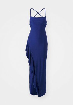 Navy blue, sleeveless dress with a fitted bodice, crisscross straps, and a ruffled side detail that cascades down the length of the skirt.