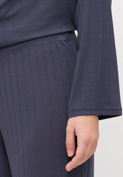 Navy blue loungewear featuring vertical stripes, long sleeves with a flared hem, and a waistband with visible stitching detail.