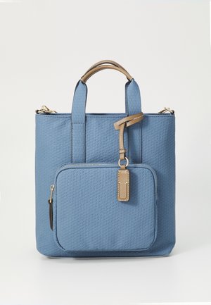 Blue textured tote bag with tan handles and front zip pocket, featuring a tan hanging tag and gold-tone metal hardware.