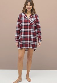 Rood en blauw geruite flanel jurk met een knoopsluiting aan de voorkant, kraag en ene enkele borstzak, voorzien van lange mouwen en een relaxte pasvorm.