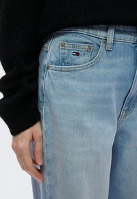 Σιελ τζιν με ελαφρώς ξεθωριασμένο πλύσιμο, με μια μικρή κόκκινη, λευκή και μπλε ετικέτα λογότυπου στην τσέπη και μεταλλικά εξαρτήματα σε κανονικό μέγεθος.