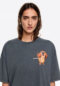 Szary, luźny t-shirt z bawełny, z kolorową grafiką jamnika na przodzie oraz napisem "BIMBA & LOLA".