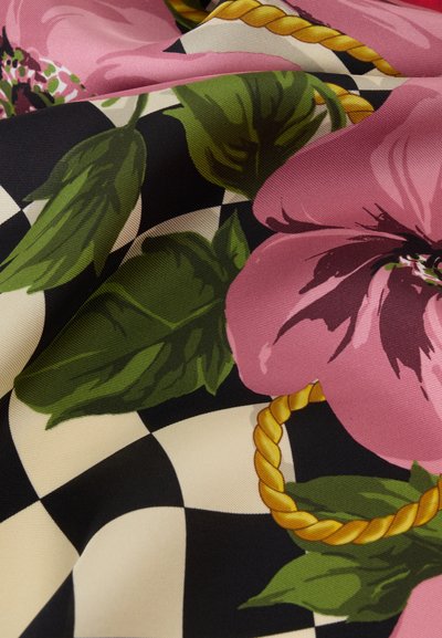 Fleurs roses et feuilles vertes sur un tissu à carreaux noir et blanc avec un motif de corde dorée, montrant les plis et la texture du matériau.