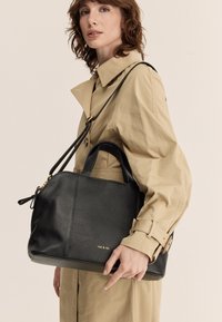 Borsa a mano in pelle nera con superficie testurizzata e manici doppi, dotata di tracolla rimovibile e accentuazione in oro con logo.