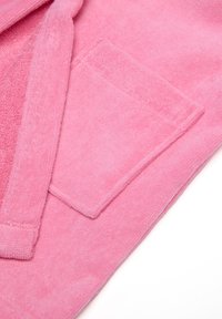 Bata de baño rosa hecha de un tejido suave y texturizado que presenta un bolsillo de parche y un cuello doblado. El diseño resalta un acabado liso y aterciopelado.