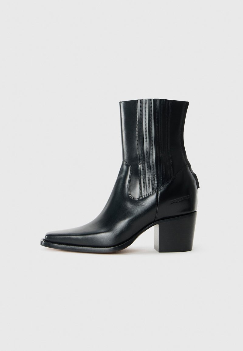 Svarta läderankelboots med spetsig tå, elastiska sidopaneler, texturerade vertikala linjer och en kraftig klack. Logotypdetalj på baksidan.