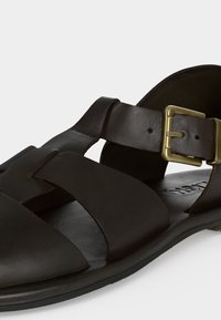 Σανδάλι ανδρικό από σκούρο καφέ δέρμα με φαρδιές λουρίδες και κλείσιμο με χρυσό αγκράφα σε επίπεδη σόλα.