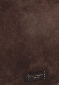 Borsa in suede marrone con superficie testurizzata e un'etichetta nera con testo bianco che riporta "GIANNI CHIARINI FIRENZE." Design semplice e rettangolare.