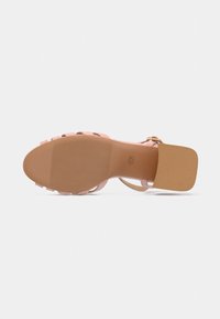 Ροζ πέδιλο με τακούνι, λείο άνω μέρος, λεπτές λουρίδες και υφασμένο πέλμα. Διαθέτει τετράγωνο τακούνι και εσωτερική σόλα σε αντίθετο χρώμα.