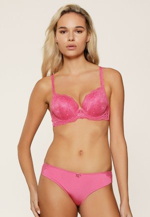 Roze kanten bh met voorgevormde cups en verstelbare bandjes, voorzien van bloemenpatronen en een decoratieve strik in het midden. Bijpassende roze slip inbegrepen.