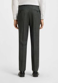 Pantaloni grigio scuro con una sottile trama, pieghe sul davanti e tasche posteriori. Indossati con una camicia bianca e scarpe nere.