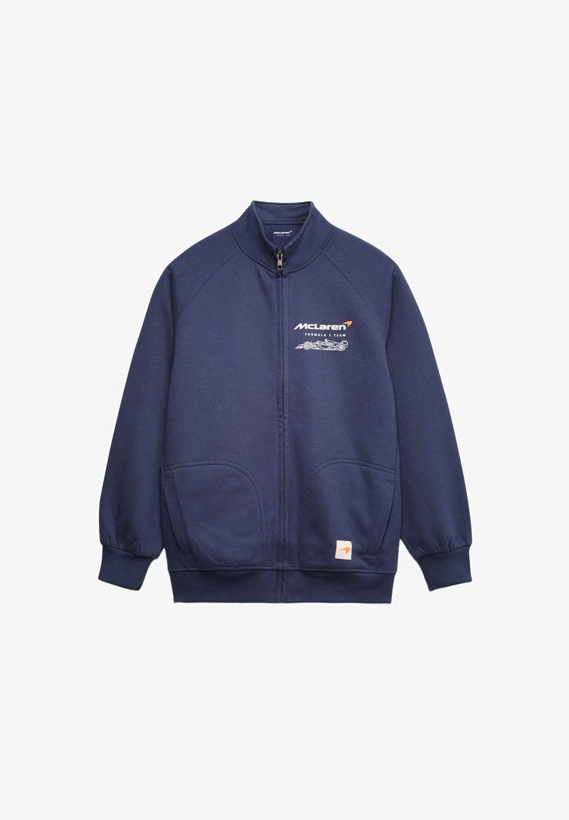 Sweat-shirt à fermeture éclair marine avec manches raglan, deux poches avant et logo McLaren ; fabriqué en tissu doux et texturé. Présente des accents orange.