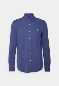 Herrskjorta med långa ärmar i marinblått med knäppt krage och en liten vit broderad logotyp på vänster bröst.