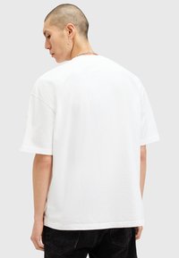 White cotton t-shirt with short sleeves, relaxed fit, curved hem, and smooth texture. The back is plain without graphics or accents.
