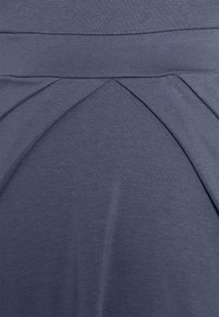 Top de tanque cinza escuro com um design pregueado na cintura, feito de um tecido macio e elástico com uma textura suave e um brilho sutil.