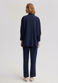 Camisa de marinero con mangas largas y acentos de botones, combinada con pantalones navy a juego. Textura suave con un ajuste relajado y corte recto.