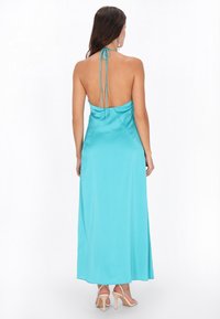 Teal sjaal maxi-jurk met verstelbare halternek, open rug en vloeiende rok. Soepele textuur, minimalistisch ontwerp en elegante silhouet.