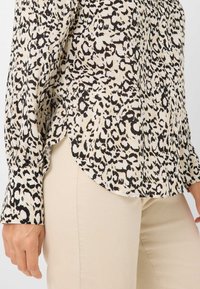 Blouse met luipaardprint in lichtbeige en zwart, met lange mouwen, een ronde zoom en knoopmanchetten, gemaakt van lichte stof.