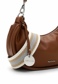 Brown leather handbag with a textured finish, featuring a decorative multi-colored woven strap and a silver logo tag. Zippered top closure.