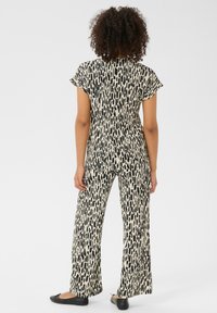 Ensemble deux pièces noir et crème à motifs, comprenant un haut à manches courtes et un pantalon ample, avec une texture lisse et une coupe décontractée.