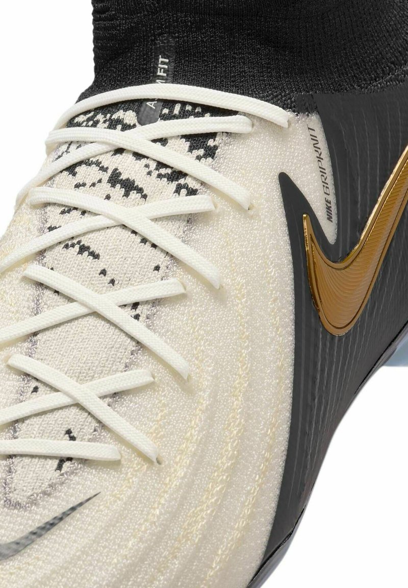 Sportschuhe mit einem Obermaterial aus weißen und schwarzen Strick, Schnürsenkeln und einem schwarzen Sockenkragen. Akzentuiert mit einem goldenen Nike-Swoosh und einer strukturierten schwarzen Seite.