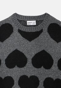 Γκρι πλεκτό πουλόβερ με μεγάλα μαύρα μοτίβα καρδιάς. Λαιμόκοψη με ριμπ τελείωμα. Μαλακή υφή, ετικέτα ορατή στη λαιμόκοψη.