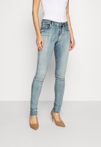 Ljusblå denimjeans med en figursydd design och medelhög midja. De har en klassisk femficksmodell och subtila urtvättning. Matchas med beiga högklackade skor.