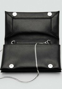 Bolso de mano negro de cuero con un acabado texturizado, que cuenta con herrajes de presión plateados, un bolsillo con cremallera y una correa de cadena plateada.