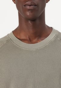 Hellgrüner, gerippt gestrickter Pullover mit Rundhalsausschnitt und strukturiertem Stoff, ausgestattet mit einem glatten Kragen und enganliegendem Schnitt.