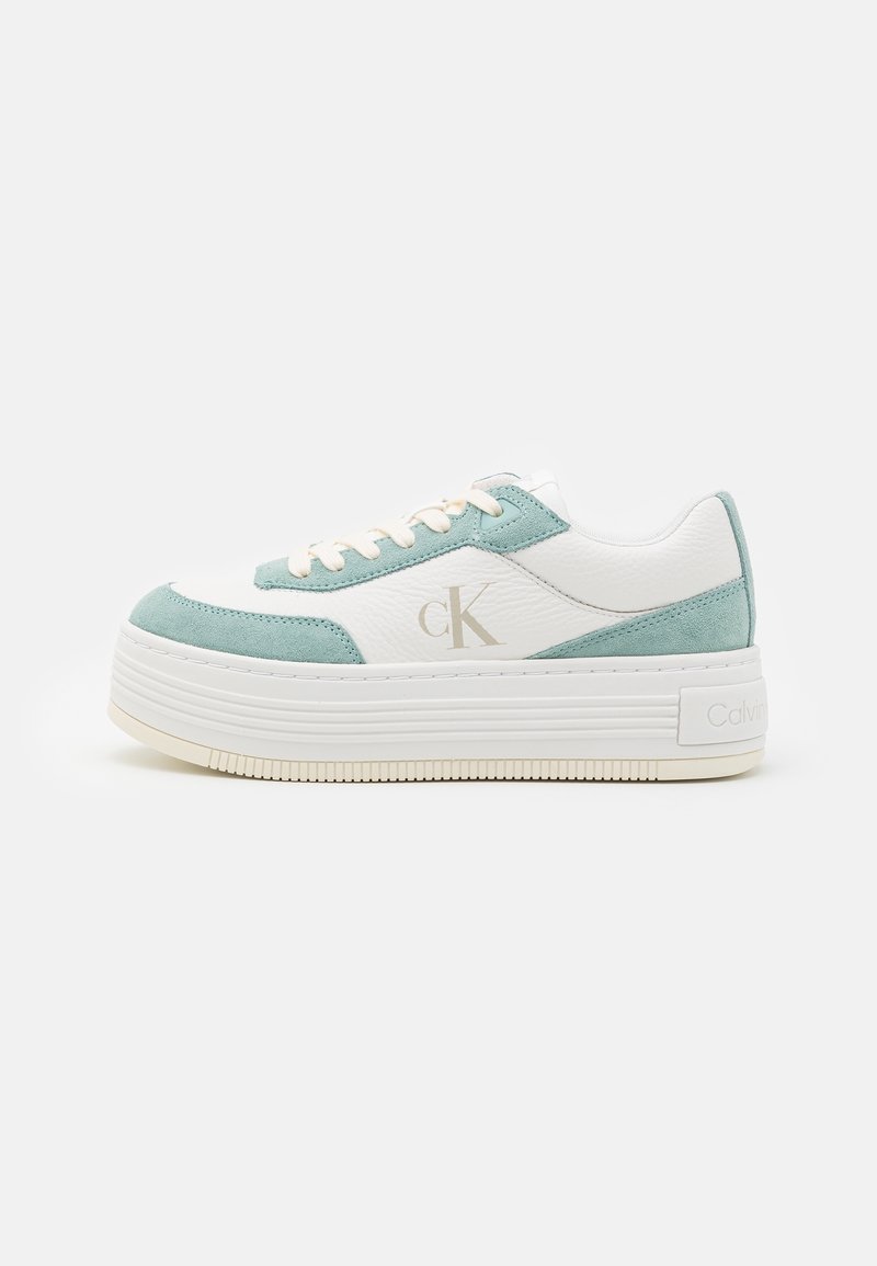 Baskets plateforme blanches et vert clair avec lacets, logo "cK" de Calvin Klein sur le côté, et semelle épaisse à rainures.