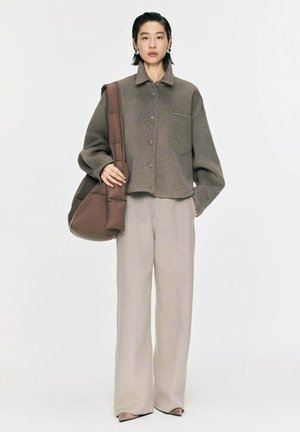 Brown wool blend button-up jacket with a pocket, paired with light beige wide-leg trousers and a brown puffy bag, featuring a smooth texture.