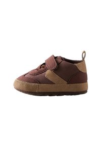 Chaussure en suède marron pour tout-petits avec une sangle Velcro, semelle en caoutchouc texturée et accents beiges ; elle présente un bout rond et un dos renforcé.
