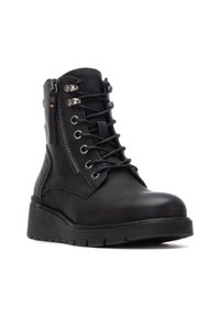 Botín de cuero negro hasta el tobillo con cordones en la parte delantera y cremallera lateral, con una suela texturizada y acentos en tono plateado.