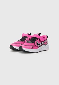 Baskets de sport roses avec lacets et bande noire, présentant une tige texturée, un swoosh Nike blanc distinct et une semelle en caoutchouc noire.
