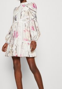 Sukienka w kwiatowy wzór z lekkiego materiału; ma bufiaste rękawy, koronkowe akcenty i dopasowaną górę, przechodzącą w rozkloszowaną spódnicę.