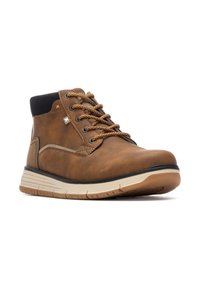 Bota de cuero marrón hasta el tobillo con cuello de tela negra, suela marrón claro y herrajes en naranja y plata contrastantes. Presenta un diseño con cordones y una textura suave.