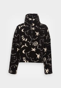 Pullover in pile nero con colletto alto, caratterizzato da motivi astratti bianchi simili a stelle e spirali, e una zip sul davanti.