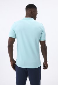 Polo shirt azzurro chiaro con maniche corte e colletto, realizzato in un tessuto morbido. Presenta un orlo dritto. Adatto per un abbigliamento informale.