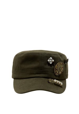 Grüne Militärmütze, verziert mit drei ornamentalen Pins, darunter ein florales Design, ein Perlen-Cluster und eine Perlen-Sicherheitsnadel.
