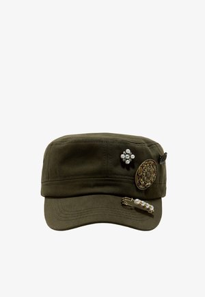 Casquette militaire verte décorée de trois épingles ornementales, comprenant un motif floral, un ensemble de perles et une épingle de sûreté en perles.