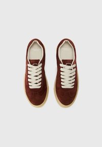 Bordeaux nubuck sneakers med kremfargede snøringer og en lys brun gummisåle, med et logo innvendig og et elegant, avrundet design.