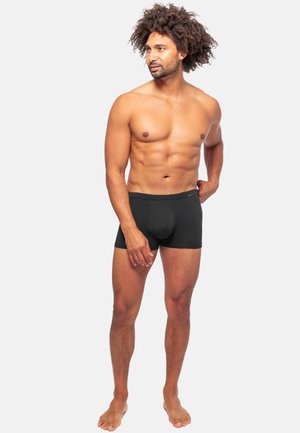 Schwarze Boxershorts mit strukturiertem Muster, enganliegendem Design und elastischem Bund, präsentiert von einem Modell mit athletischer Figur.