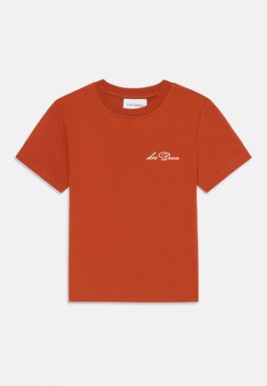 T-shirt en coton rouge à manches courtes, col rond, avec un logo blanc brodé "Les Deux" sur la poitrine. Texture lisse et design simple.