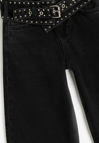 Svarta jeans gjorda av denim, med ett brett bälte med metall-nitar och en rektangulär spänne, som visar en jämn textur och en figurnära design.