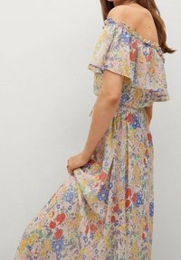 Robe florale décolletée en tissu léger et transparent avec une palette de couleurs pastel. Présente des manches froncées et une jupe fluide avec un détail fendu.